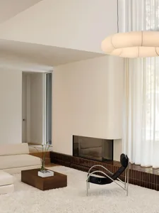 Minimalist modern living room featuring a white sofa, a black armchair, a coffee table with magazines, and a linear fireplace