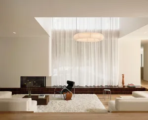 A modern living room featuring a sleek, glass wall design with minimalist decor and warm lighting.