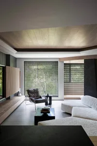 A modern living room with glass walls, a wooden floor, and a sofa.