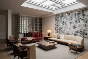 Modern living room featuring a marble coffee table surrounded by contemporary furniture and large abstract artwork on the wal