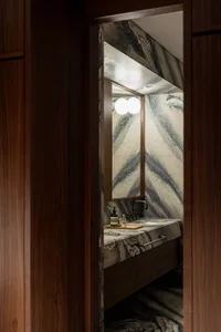 Modern bathroom with marble walls and floor, featuring a vanity sink with a floating cabinet and a large mirror with double c