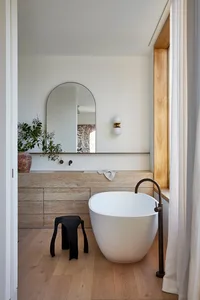 A modern bathroom featuring a freestanding tub, sink, and vanity with marble finishes and a minimalist design.