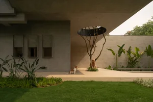 A contemporary concrete house with a minimalist design featuring a circular opening in the ceiling and a dog sitting beside a