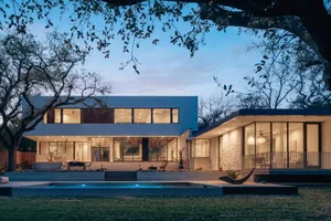 A modern residential exterior with a concrete finish and large windows.