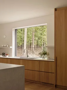 Modern residential kitchen featuring a concrete countertop and wooden cabinets.