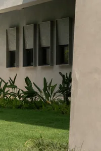 Modern architectural windows set in a concrete wall, surrounded by greenery and grass.