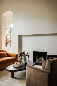 A minimalist living room featuring neutral tones, modern furniture, and a fireplace.