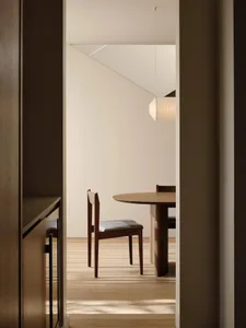 A minimalist dining room with wooden furniture and flooring.