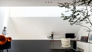 A minimalist modern office featuring a white hardwood desk, a window letting in natural light, and a white chair.