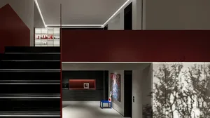 Modern entrance hall featuring a black staircase, red floating wall, white flooring, black walls, and white ceiling.