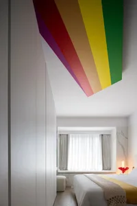 A modern bedroom with a colorful ceiling and a neatly made bed.