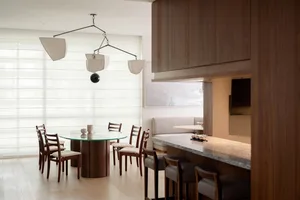 Modern living and dining space featuring wooden furniture and a glass table.