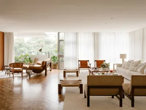 Modern minimalist living room featuring walnut furniture, glass windows, and neutral color palette.