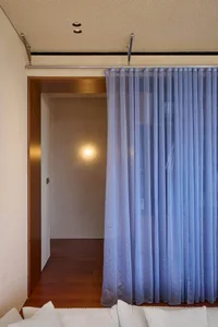 A modern minimalist living room with a window featuring sheer blue curtains.
