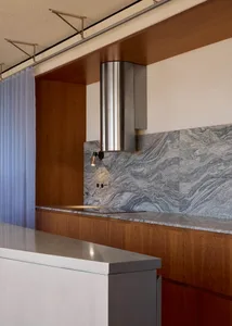 Modern kitchen featuring a minimalist design with marble countertops and a stainless steel range hood.
