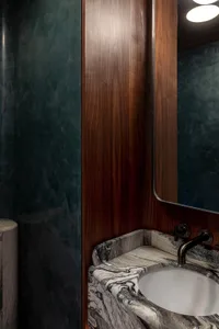 Modern industrial bathroom with marble countertop and wooden accents.
