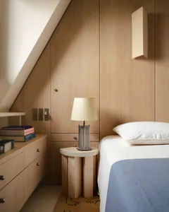 A minimalist bedroom with wooden walls and a bedside table.