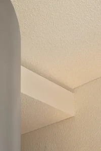 Low-angle photograph of a minimalist staircase with textured beige walls and steps.