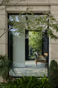 Modern entrance area with large glass windows and surrounding greenery.