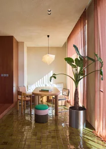 A modern living area with a tiled floor, wood furniture, and large windows allowing natural light.