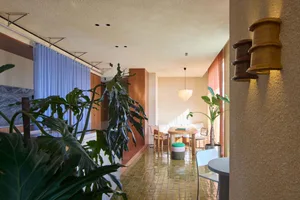 A modern living room featuring tile flooring and potted plants.