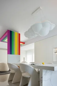 A modern kitchen with a white marble countertop, white chairs, and a colorful wall art.