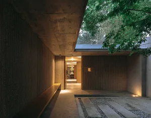 Modern residential entrance featuring concrete walls and wooden bench.