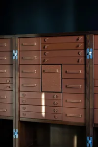 A brown leather wardrobe with multiple drawers and handles.