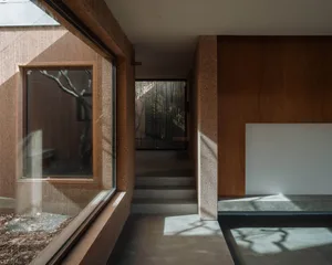 An interior space with minimalist design, featuring concrete walls, large windows, and natural light.