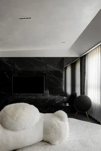 A modern bedroom with black marble walls, white furniture, and a large window.