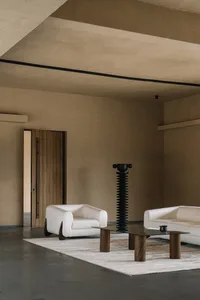 Contemporary interior design featuring a minimalist living room with white furniture and a textured concrete floor and ceilin