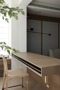 A modern industrial home office with a long wooden desk, black light fixture, and green plant.