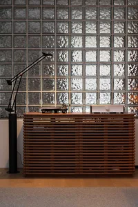A modern industrial interior design featuring glass block walls and wooden furniture.