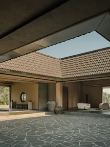 A modern living room with concrete walls, a stone floor, and a skylight.