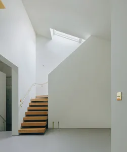 Modern interior with a staircase featuring concrete walls, wooden steps, and concrete steps illuminated by a skylight with a 