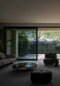 Modern living room featuring grey sofa, black coffee table, and large windows with a view of greenery.