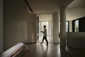 A modern minimalist interior space with a metallic fireplace and glass windows.