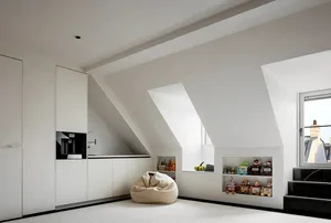 Modern minimalist living room featuring white walls, a kitchenette, and a window seat with toys.