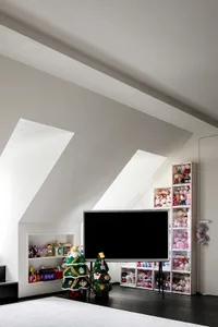 A minimalist playroom with a television, shelves filled with stuffed animals, and Christmas decorations.
