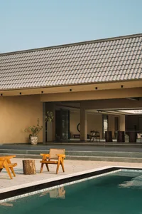 Outdoor residential area featuring a tiled roof, wooden furniture, and a swimming pool.