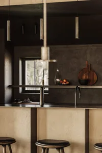 Minimalist kitchen with metallic countertops and stools, featuring sleek, modern design elements.