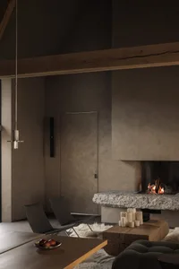 A minimalist living room with concrete walls, a stone fireplace, wooden furniture, and a white fur rug.