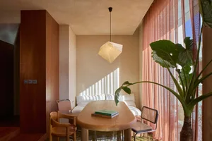 A minimalist sitting room with wooden furniture and large windows.