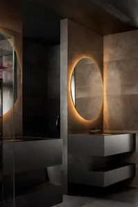 A modern bathroom featuring concrete walls, metal fixtures, and glass elements.