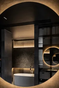 A modern bathroom featuring metallic grey tiles, black marble accents, and concrete surroundings.