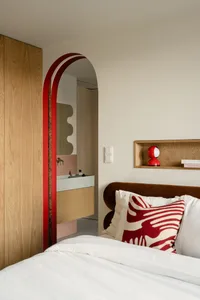 Contemporary bedroom featuring light wooden cabinets, ceramic tiles, and a plush bed with red and white decorative pillows.