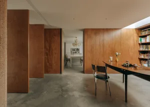 A modern dining room with wooden walls, a wooden dining table, and a concrete floor.