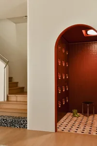 Modern entryway featuring red terrazzo tiles and a small black stool with green boots.