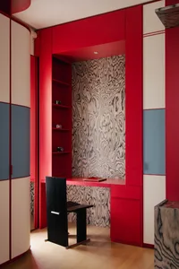 A modern home office with red walls, a black chair, and a wooden textured wall.