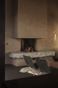 A modern living room featuring a stone and concrete fireplace